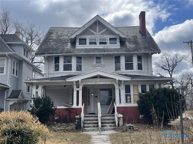 traditional style home with covered porch, brick siding, and a chimney