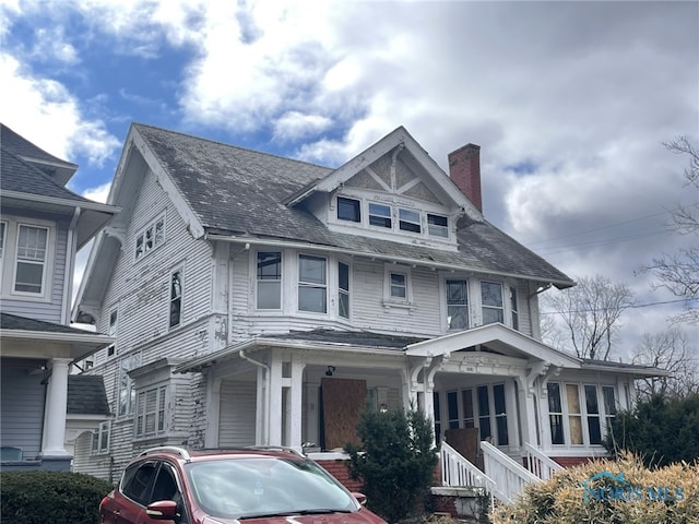 american foursquare style home featuring covered porch and a chimney