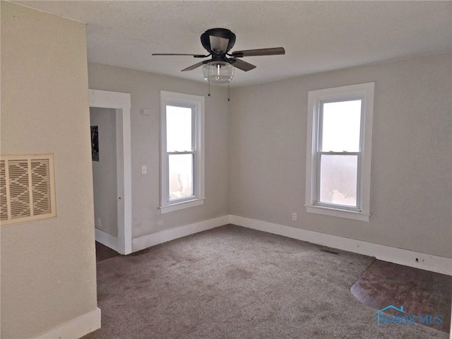 spare room with carpet floors, baseboards, visible vents, and ceiling fan