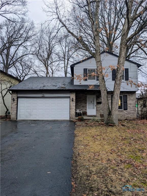 view of front of house with aphalt driveway, brick siding, and an attached garage