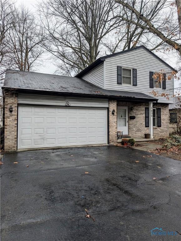 traditional home with a garage, driveway, and brick siding