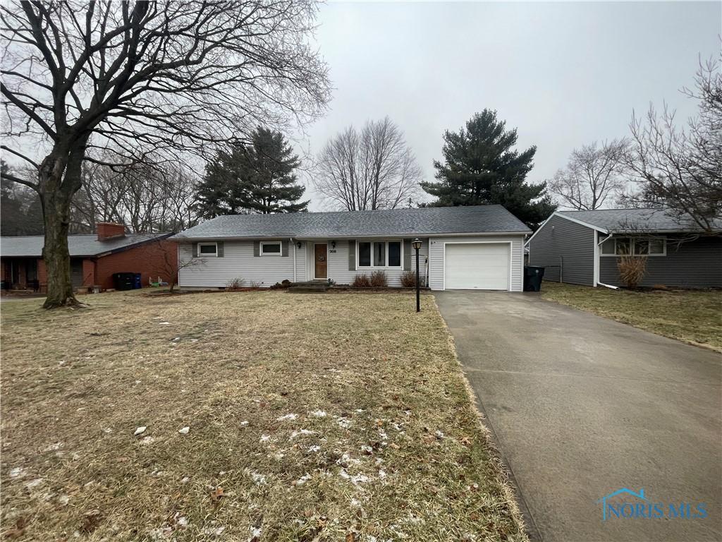 single story home featuring driveway, a front lawn, and an attached garage