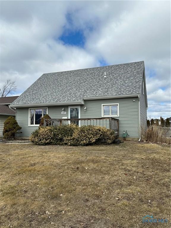 back of property featuring a shingled roof, a wooden deck, and a yard