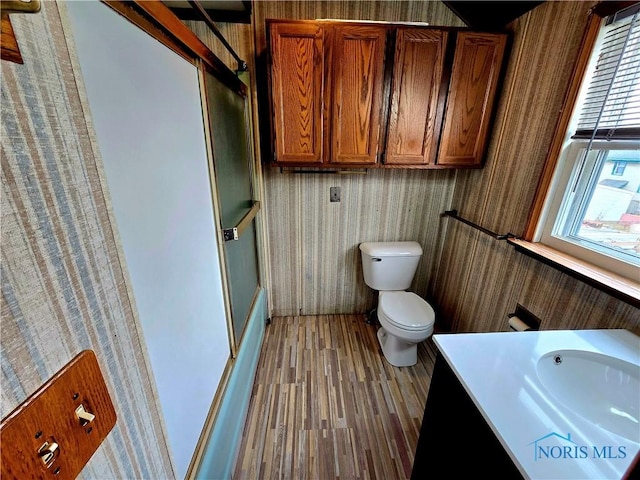 bathroom with shower / bath combination with glass door, vanity, toilet, and wood finished floors