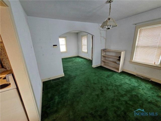 unfurnished dining area with arched walkways, baseboards, visible vents, and dark colored carpet