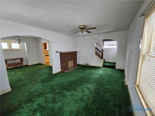 unfurnished living room featuring arched walkways, carpet floors, stairway, and baseboards