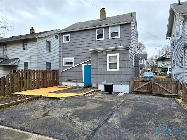 rear view of house with a chimney, a gate, a patio area, fence, and cooling unit