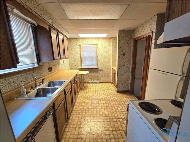 kitchen featuring white appliances, a sink, light countertops, light floors, and wallpapered walls