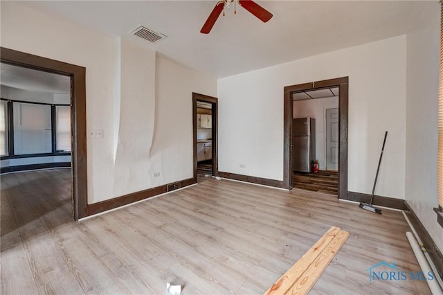 unfurnished bedroom with baseboards, visible vents, wood finished floors, and freestanding refrigerator