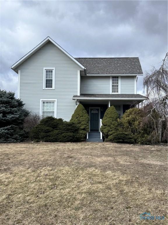 traditional home featuring a shingled roof and a front lawn