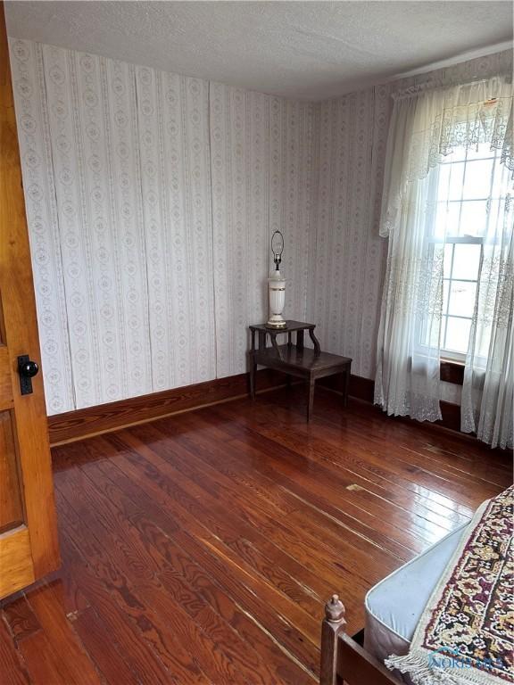 interior space with hardwood / wood-style flooring, baseboards, and wallpapered walls