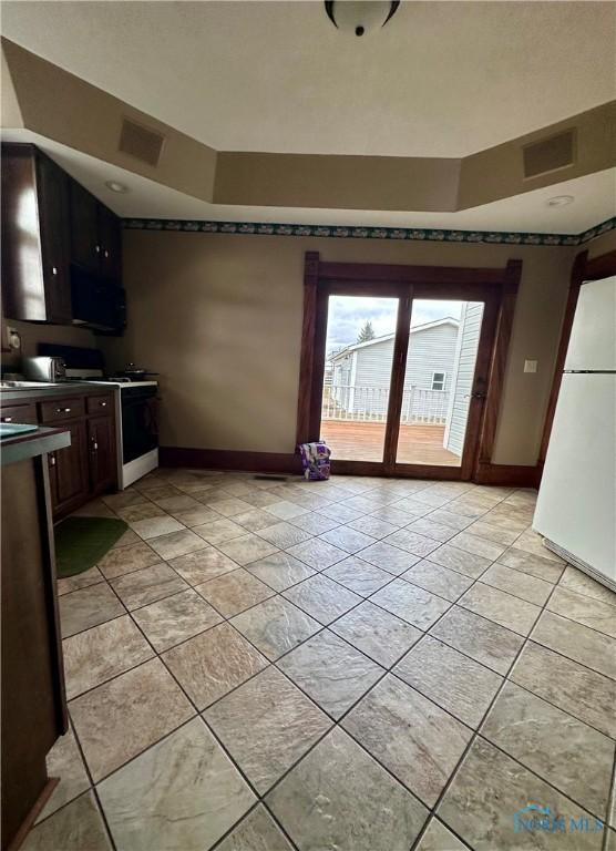 kitchen with white appliances, light tile patterned flooring, visible vents, and baseboards