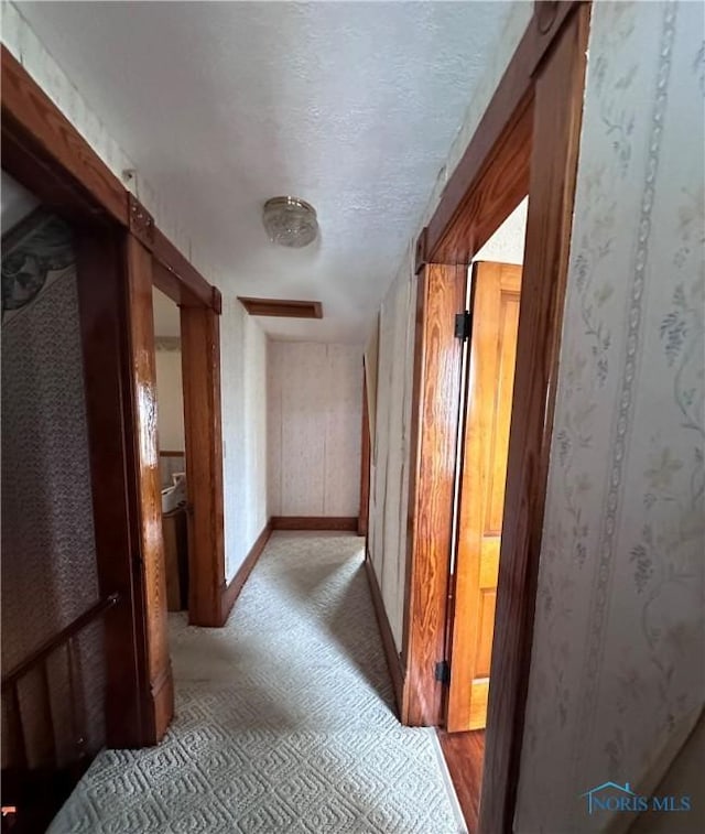 hallway featuring a textured ceiling and baseboards