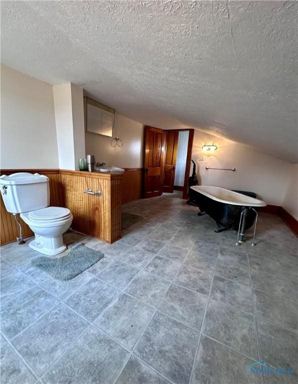 bathroom featuring wainscoting, a textured ceiling, and toilet