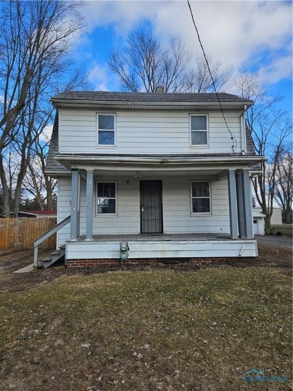 view of front facade featuring a porch, fence, and a front lawn