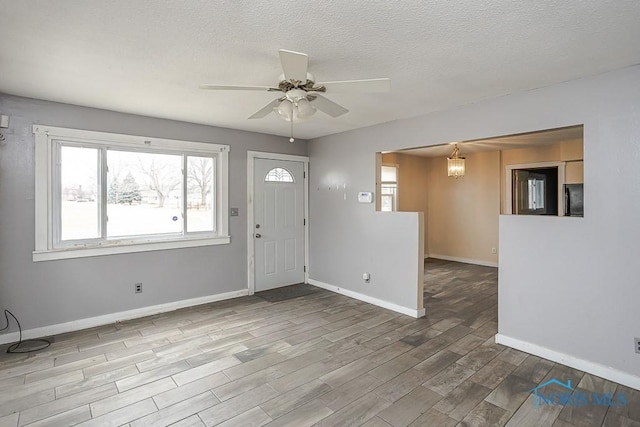 foyer featuring a ceiling fan, a textured ceiling, baseboards, and wood finished floors