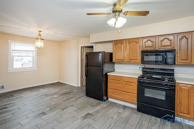 kitchen featuring light countertops, hanging light fixtures, visible vents, light wood-type flooring, and black appliances