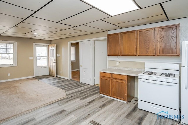 kitchen with white appliances, baseboards, light wood-style flooring, brown cabinets, and light countertops