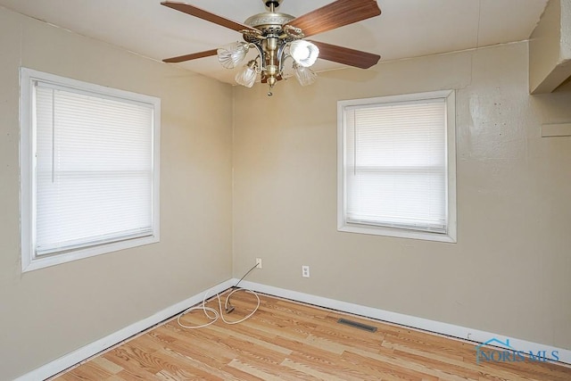 unfurnished room featuring visible vents, baseboards, and wood finished floors