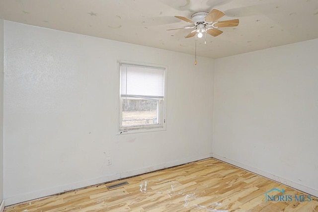 empty room with visible vents, light wood finished floors, a ceiling fan, and baseboards