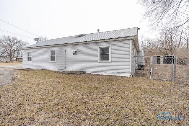 back of house with a gate, metal roof, a lawn, and fence