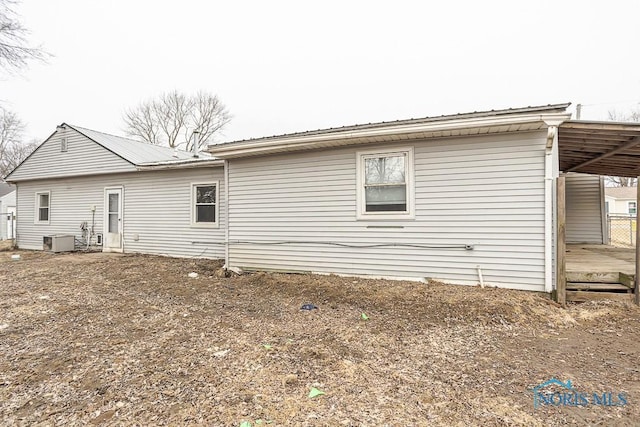 back of property featuring a carport, metal roof, and cooling unit