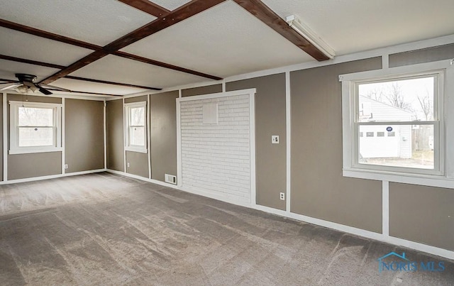 carpeted spare room featuring ceiling fan, visible vents, and beam ceiling