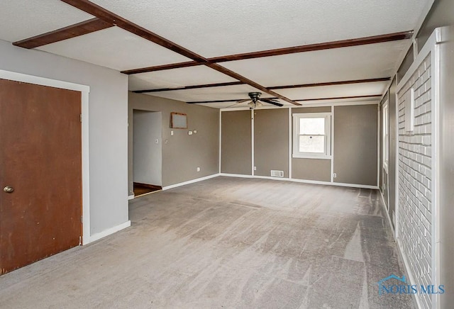 carpeted empty room featuring a ceiling fan, visible vents, a textured ceiling, and baseboards