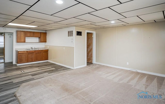 interior space featuring a sink, visible vents, baseboards, light countertops, and brown cabinets