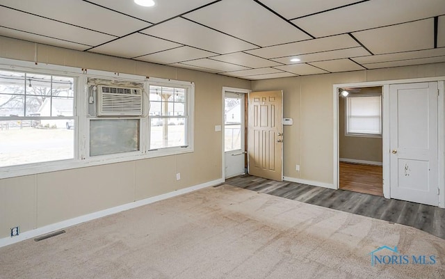 carpeted empty room featuring recessed lighting, visible vents, wood finished floors, a wall mounted air conditioner, and baseboards