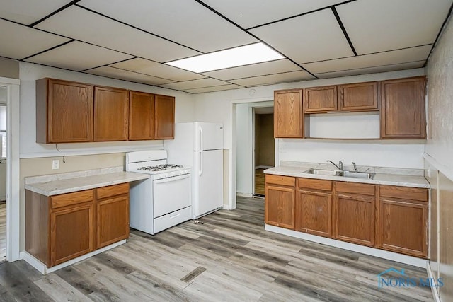 kitchen featuring white appliances, light wood-style floors, a sink, and light countertops