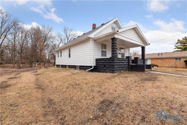 view of side of home featuring a porch and a chimney