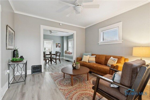 living area featuring plenty of natural light, light wood-style flooring, and crown molding