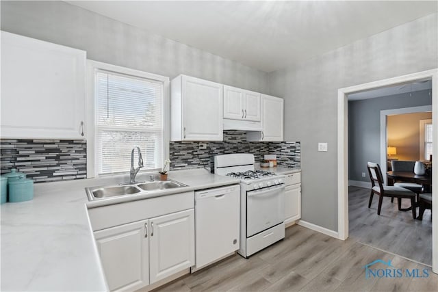 kitchen with white appliances, white cabinets, light countertops, light wood-type flooring, and a sink