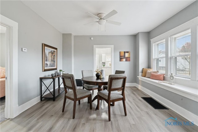 dining area featuring light wood-type flooring, baseboards, visible vents, and a ceiling fan