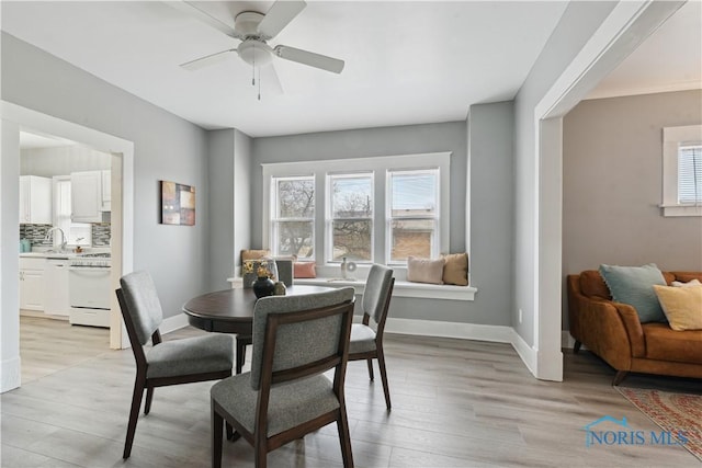 dining room with light wood-style floors, a wealth of natural light, and baseboards