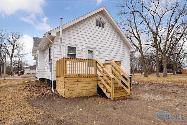 back of house featuring roof with shingles and a wooden deck