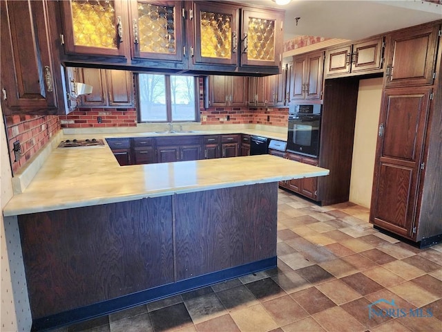 kitchen featuring decorative backsplash, light countertops, a peninsula, and black appliances