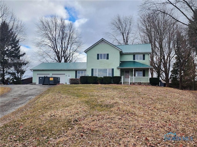 traditional home featuring a porch, an attached garage, metal roof, a front lawn, and driveway