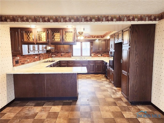 kitchen with cooktop, light countertops, a peninsula, and under cabinet range hood