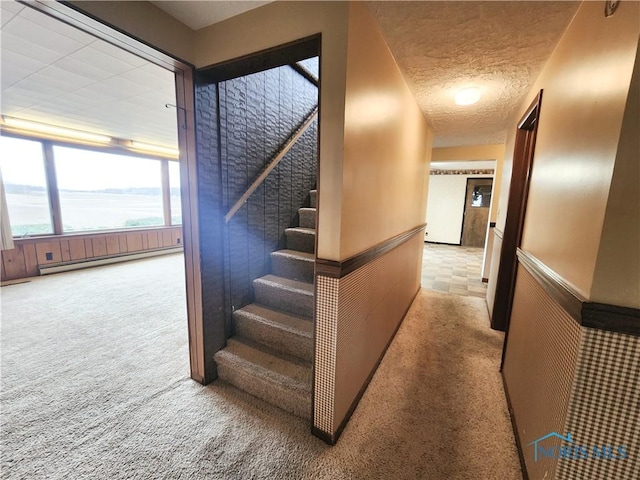 corridor with carpet floors, a baseboard radiator, stairway, and a textured ceiling