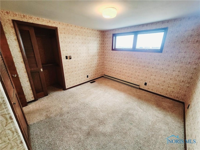 unfurnished bedroom with a baseboard heating unit, visible vents, light colored carpet, and wallpapered walls