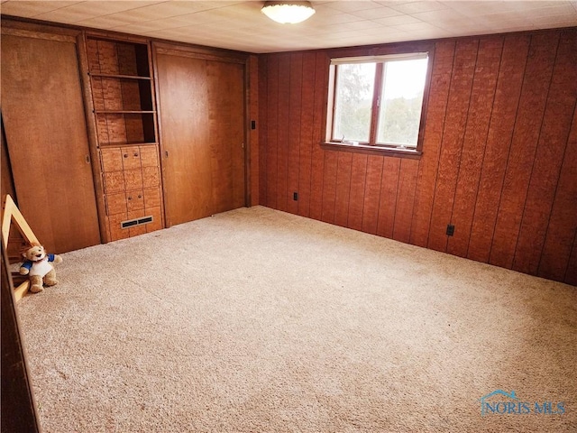 unfurnished bedroom featuring wood walls and carpet