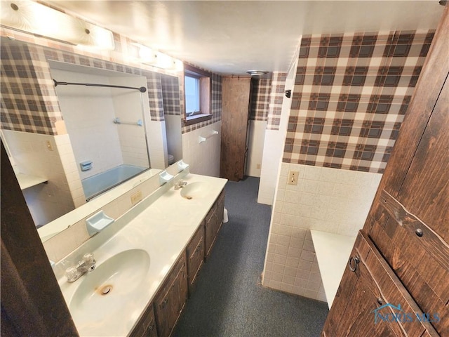 bathroom with a shower, a sink, tile walls, and double vanity