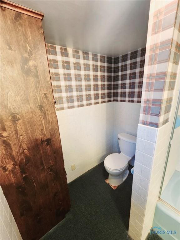 bathroom with wallpapered walls, toilet, and walk in shower