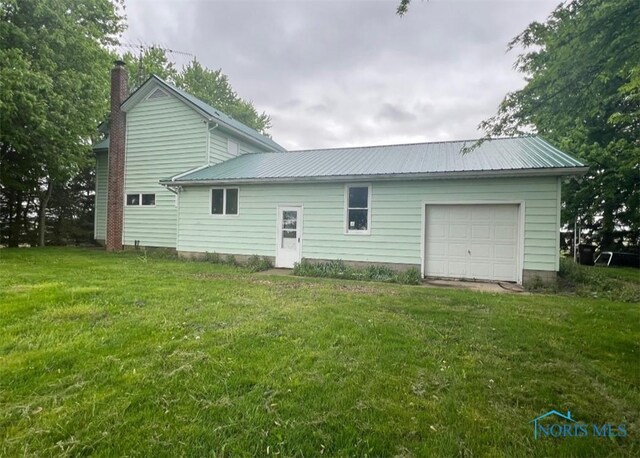 3221 Carrell Rd, Bucyrus, OH 44820 - rear view of property featuring a garage, metal roof, a chimney, and a yard
