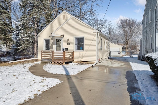 view of front of property with central air condition unit, a garage, an outdoor structure, a wooden deck, and a gate