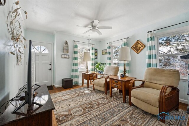 sitting room featuring a ceiling fan, crown molding, baseboards, and wood finished floors