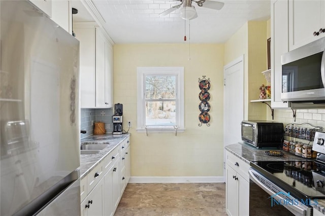 kitchen featuring backsplash, appliances with stainless steel finishes, white cabinetry, a sink, and light stone countertops