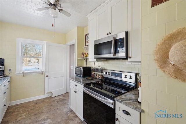 kitchen featuring stainless steel appliances, backsplash, a ceiling fan, white cabinets, and dark stone countertops